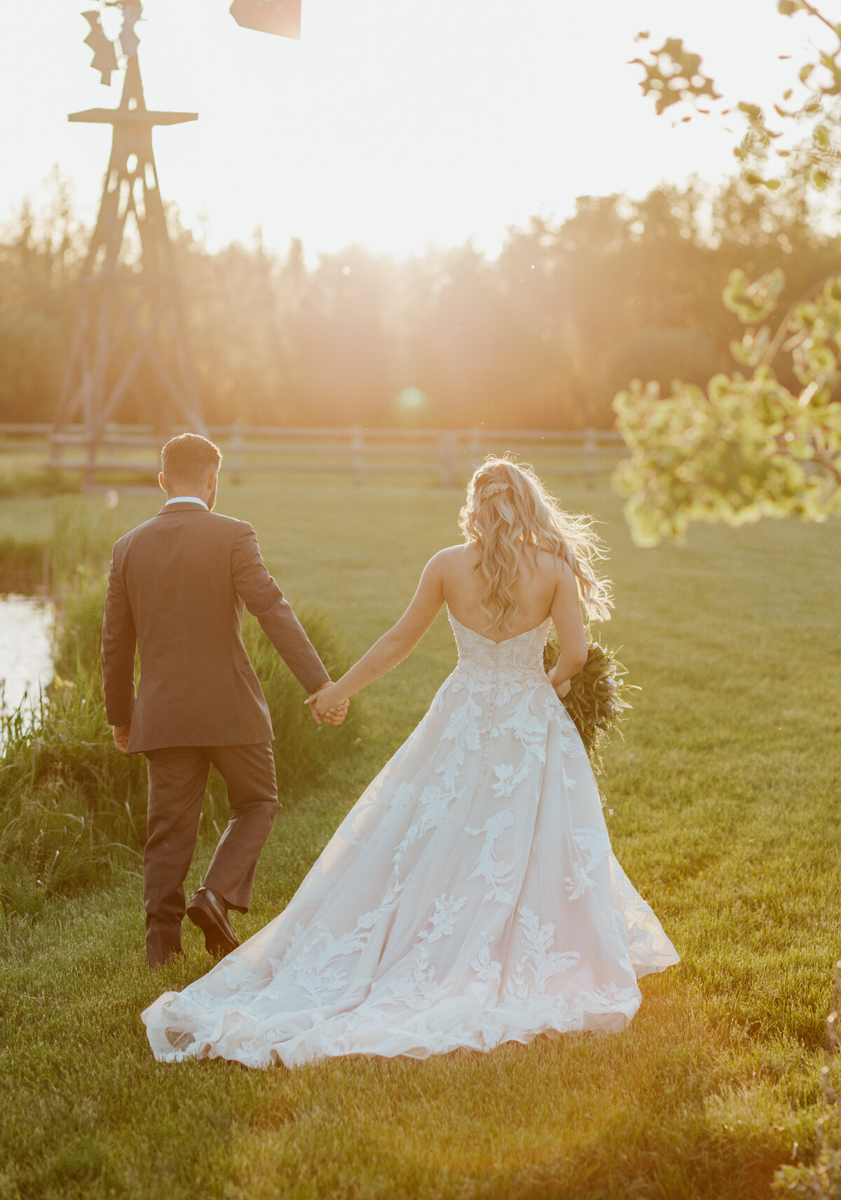 bride and groom holding hands by lake