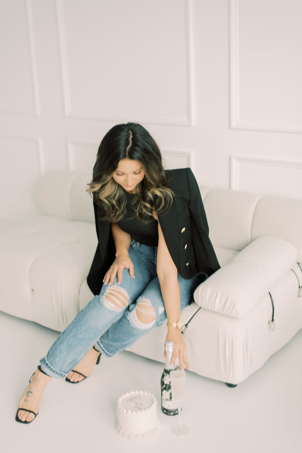 Relaxed yet polished portrait of spa manager in black, seated in a minimal studio