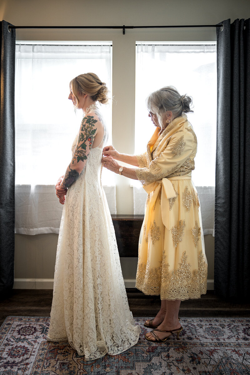 A heartfelt moment as the mother of the bride helps fasten the back of her daughter’s dress in the charming Ridgefield redwood grove. This intimate wedding preparation scene captures the love and support shared on this special day in Arcata. Perfect for highlighting Ridgefield weddings and family-focused moments.