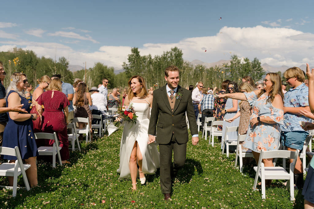 bride and groom celebrating as they walk back up the aisle surrounded by their guests