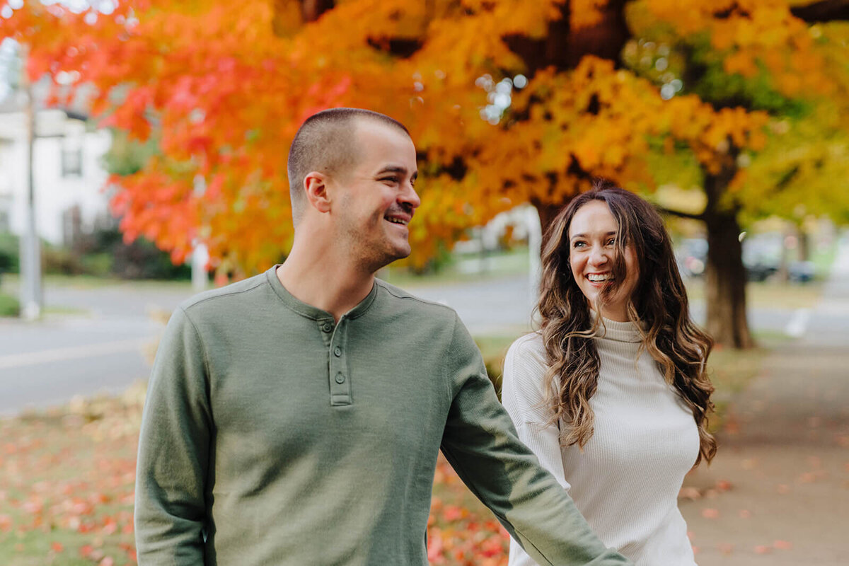 Couple walking along under a tree at Finger Lakes engagement session