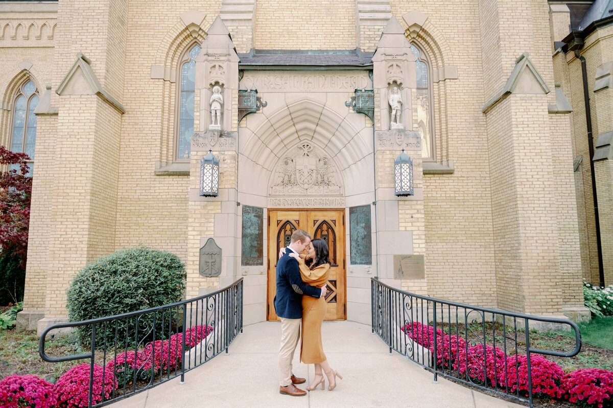 engaged couple touching foreheads in front of an ornate building