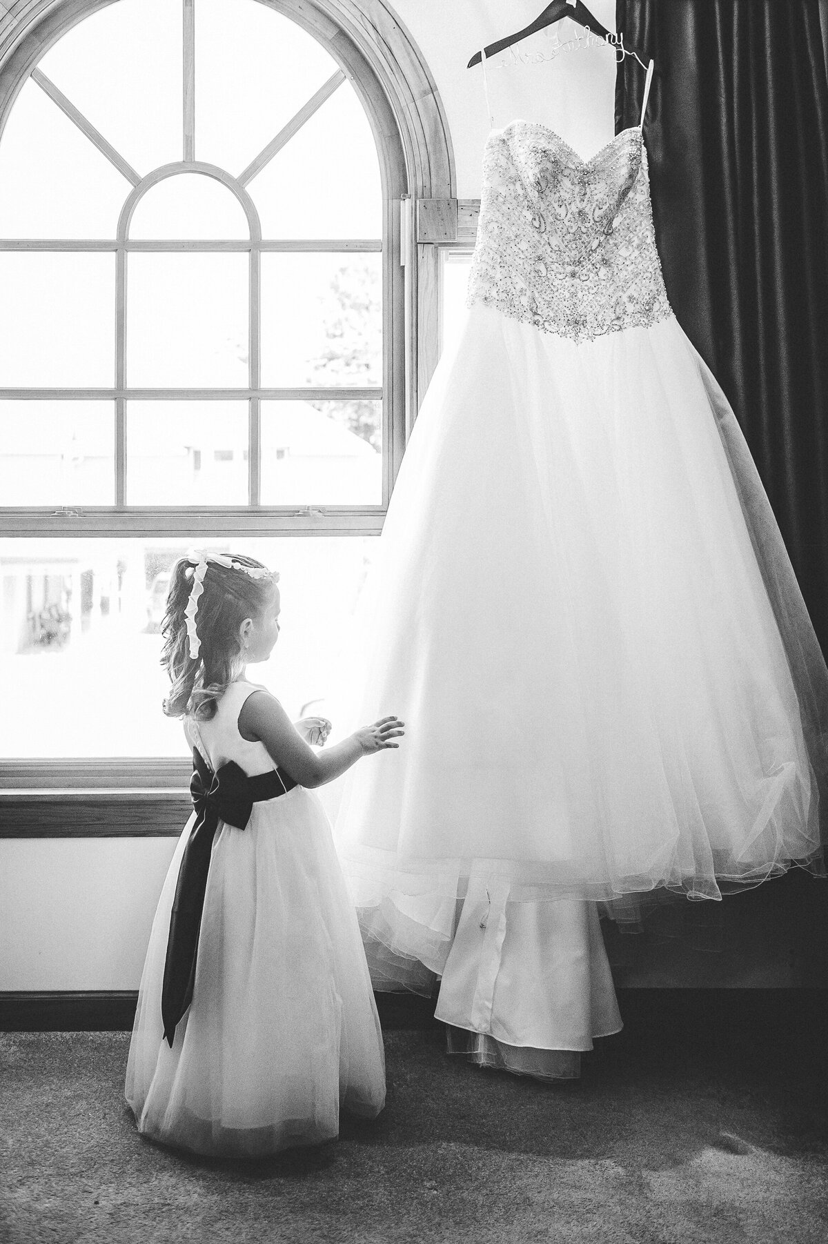 Flower girl playing with brides wedding dress.