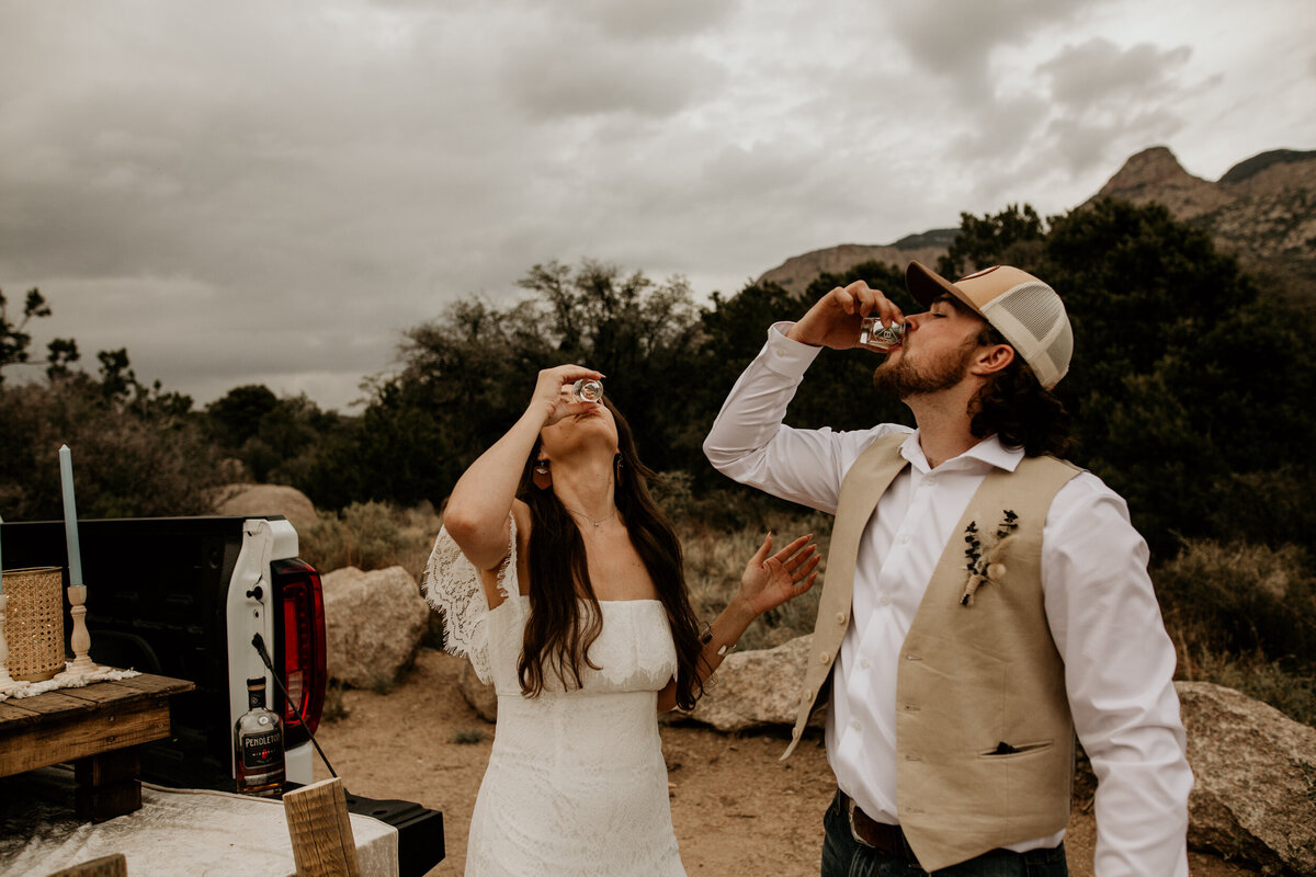 newlyweds taking a shot of whiskey  at the Sandia mountain foothills