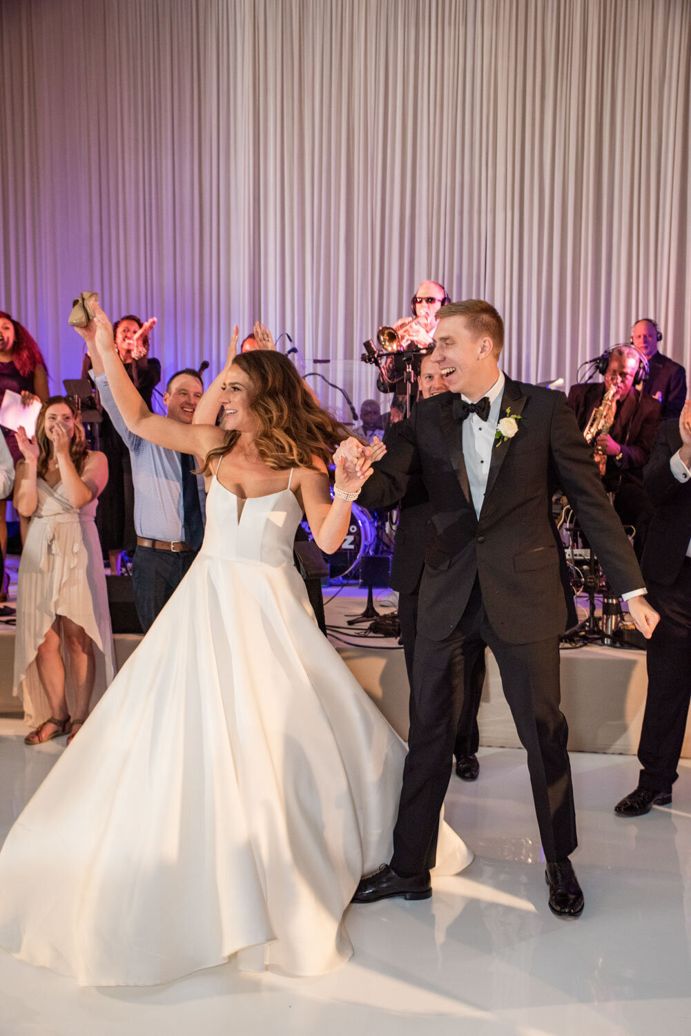 A bride and groom are dancing in front of a band