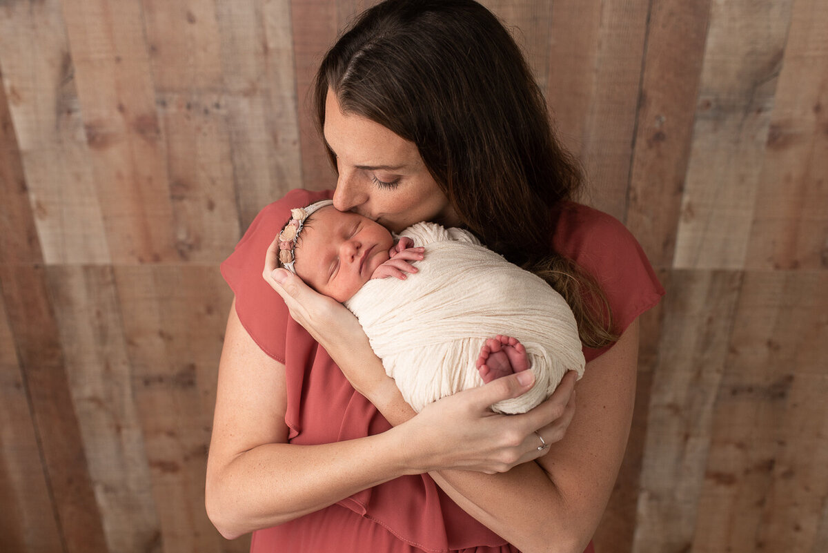 Close up of mother kissing baby daughter at newborn session in Canton, Connecticut