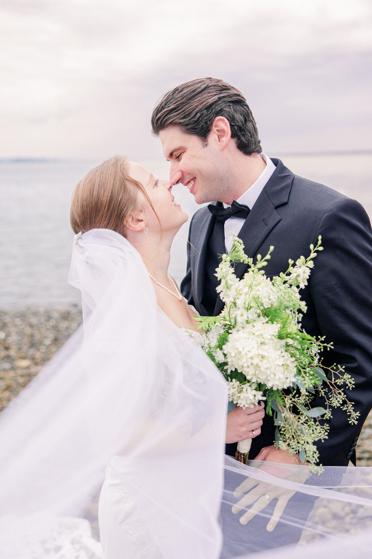 Bride and groom smiling with veil blowing in the breeze representing romantic Boston wedding images