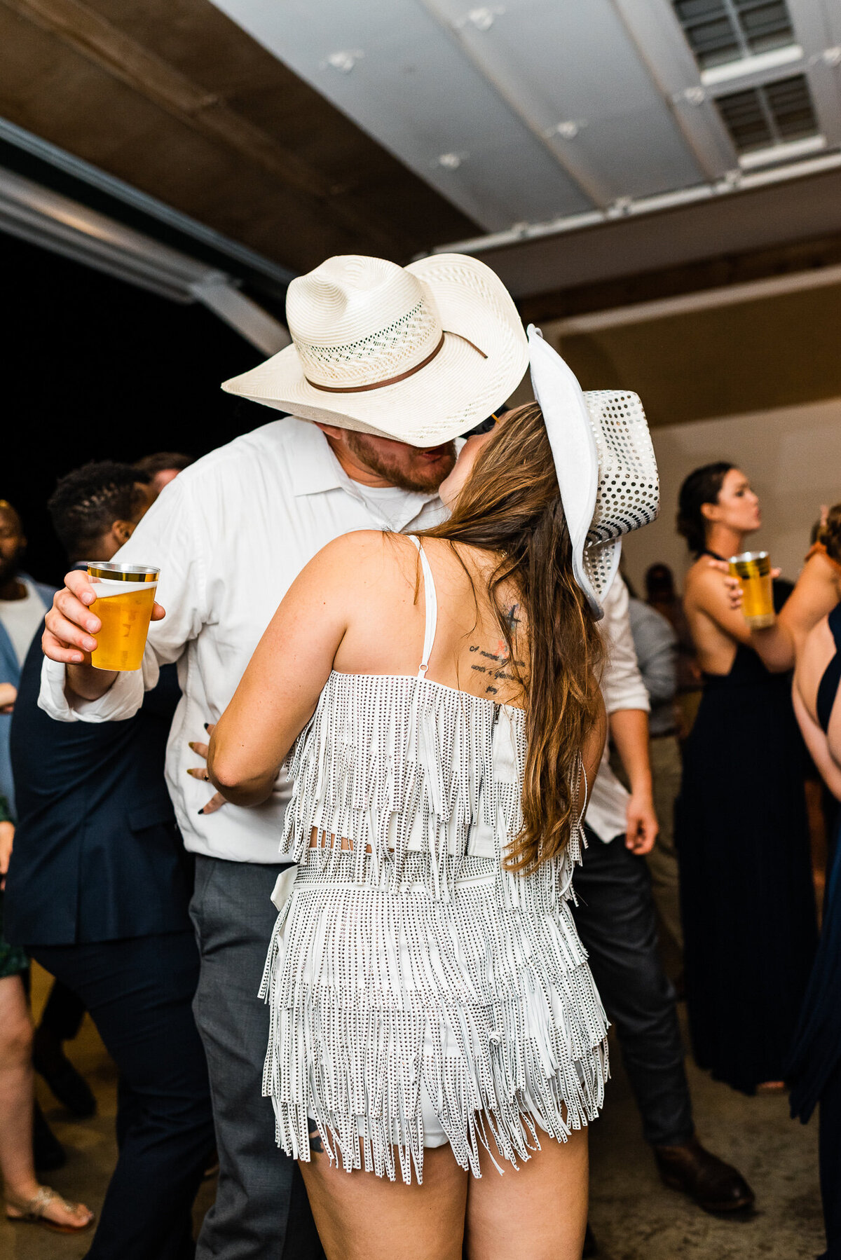 Virginia wedding photographer captures bride and groom both in cowboy hats kissing on the dance floor during their wedding reception