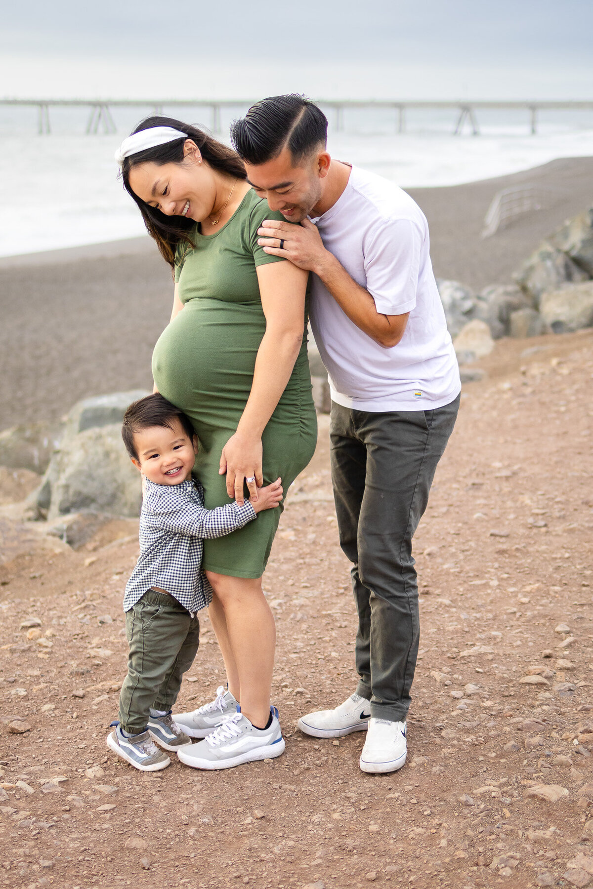 Bay Area Maternity Portfolio - Ellobelle Photography with a smiling toddler hugging mom’s bump while both parents look on lovingly