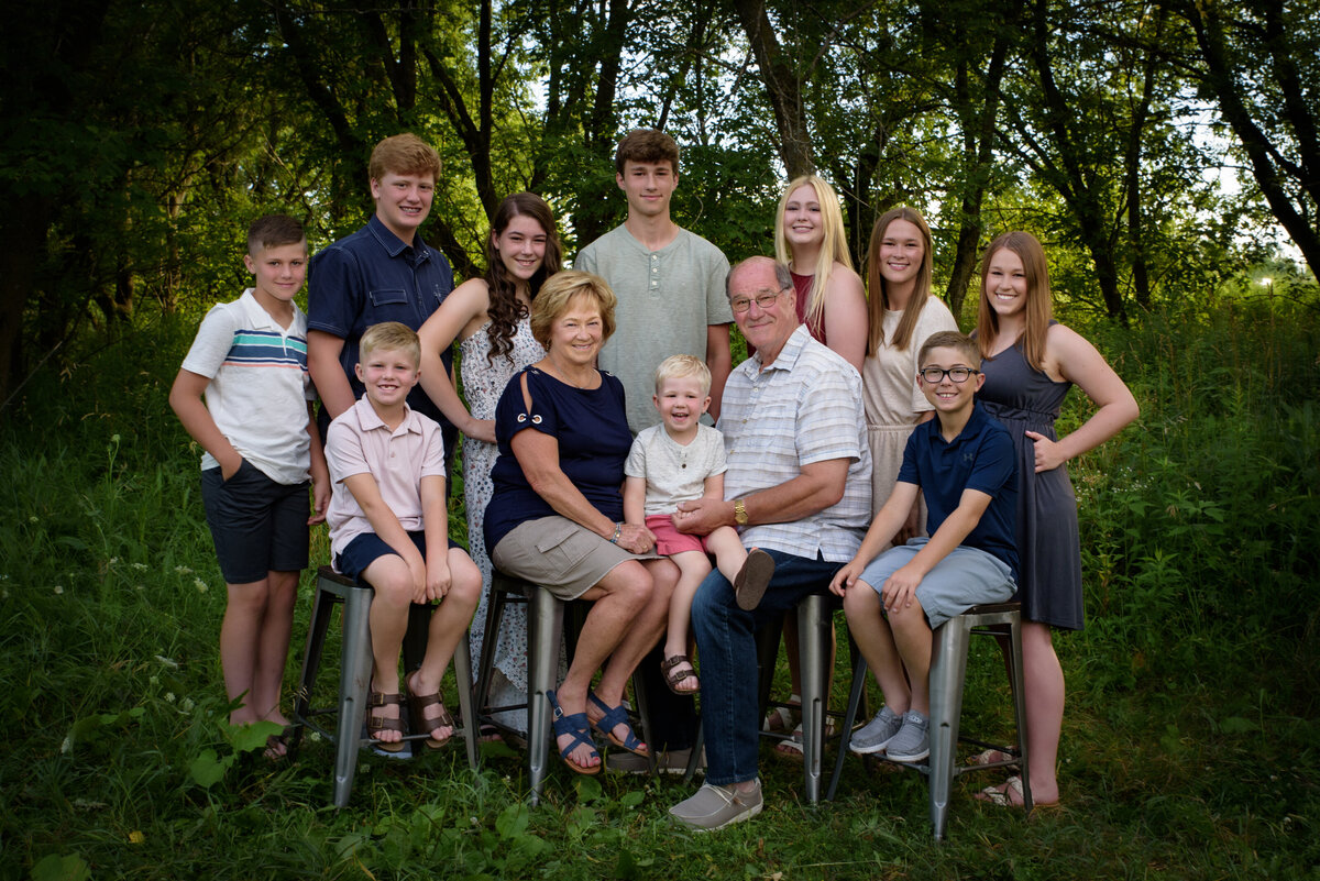 Large extended family portrait with grandparents and their grandchildren sitting in grassy area at Fonferek Glen County Park near Green Bay, Wisconsin
