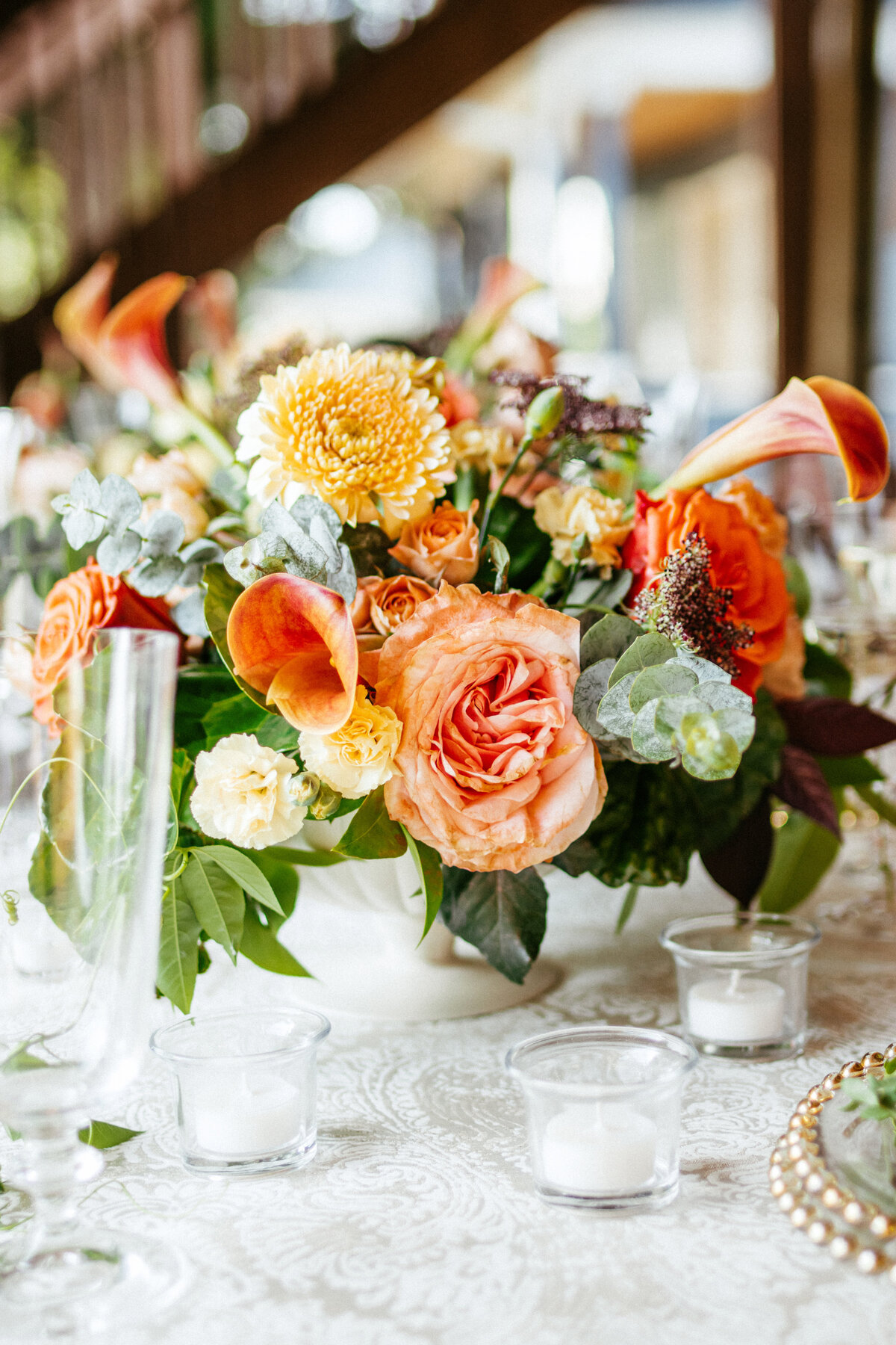 orange rose and calla lily centerpiece with white votive candles