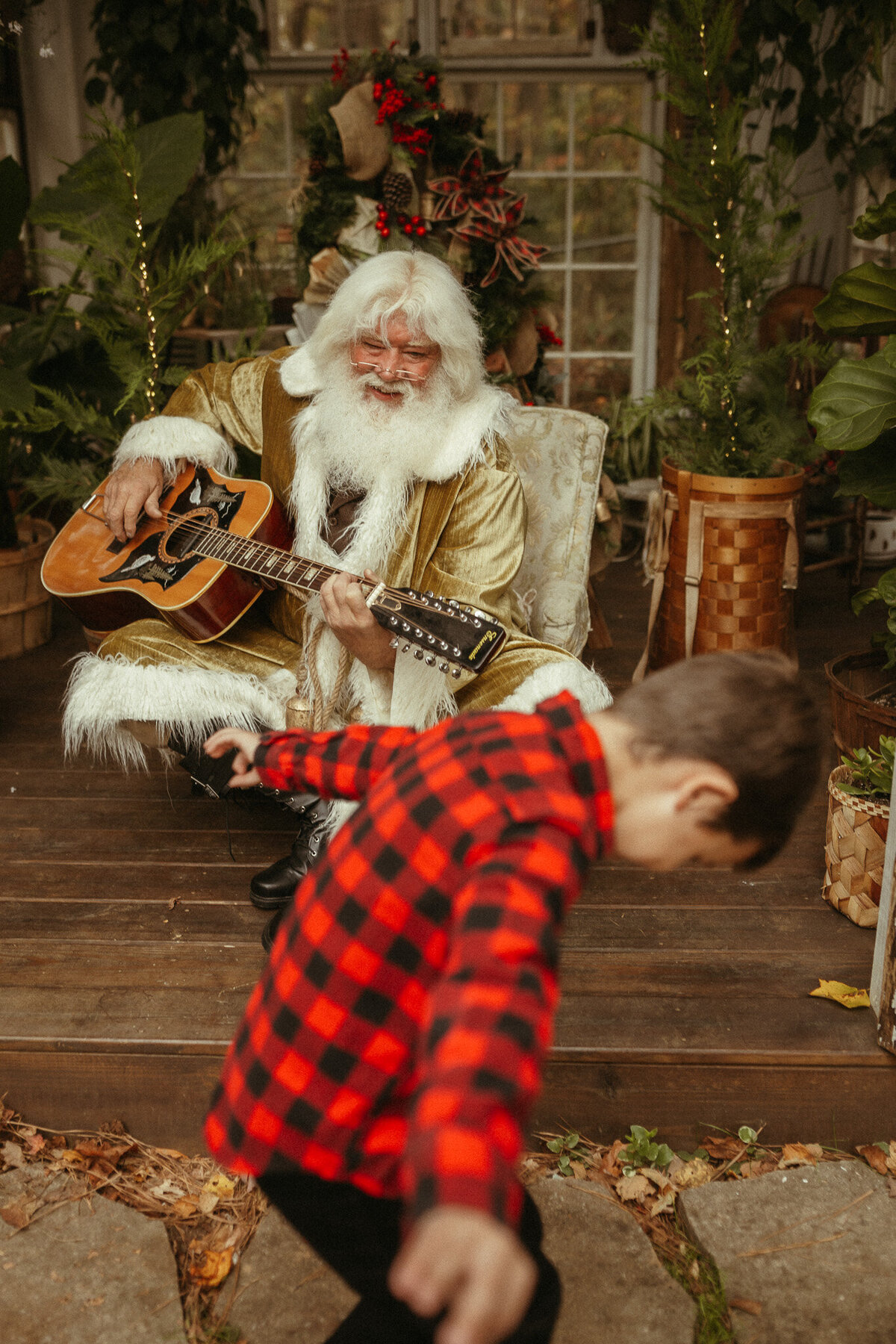 A little boy in red and black gingham pajamas dances around while Santa plays guitar at Das Hinterhaus in Marietta, GA.  