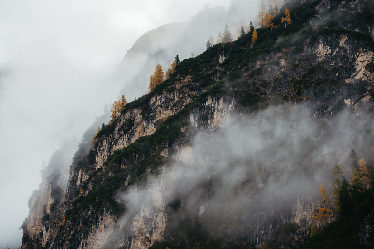 Clouds rolling over mountain ridge with autumn trees