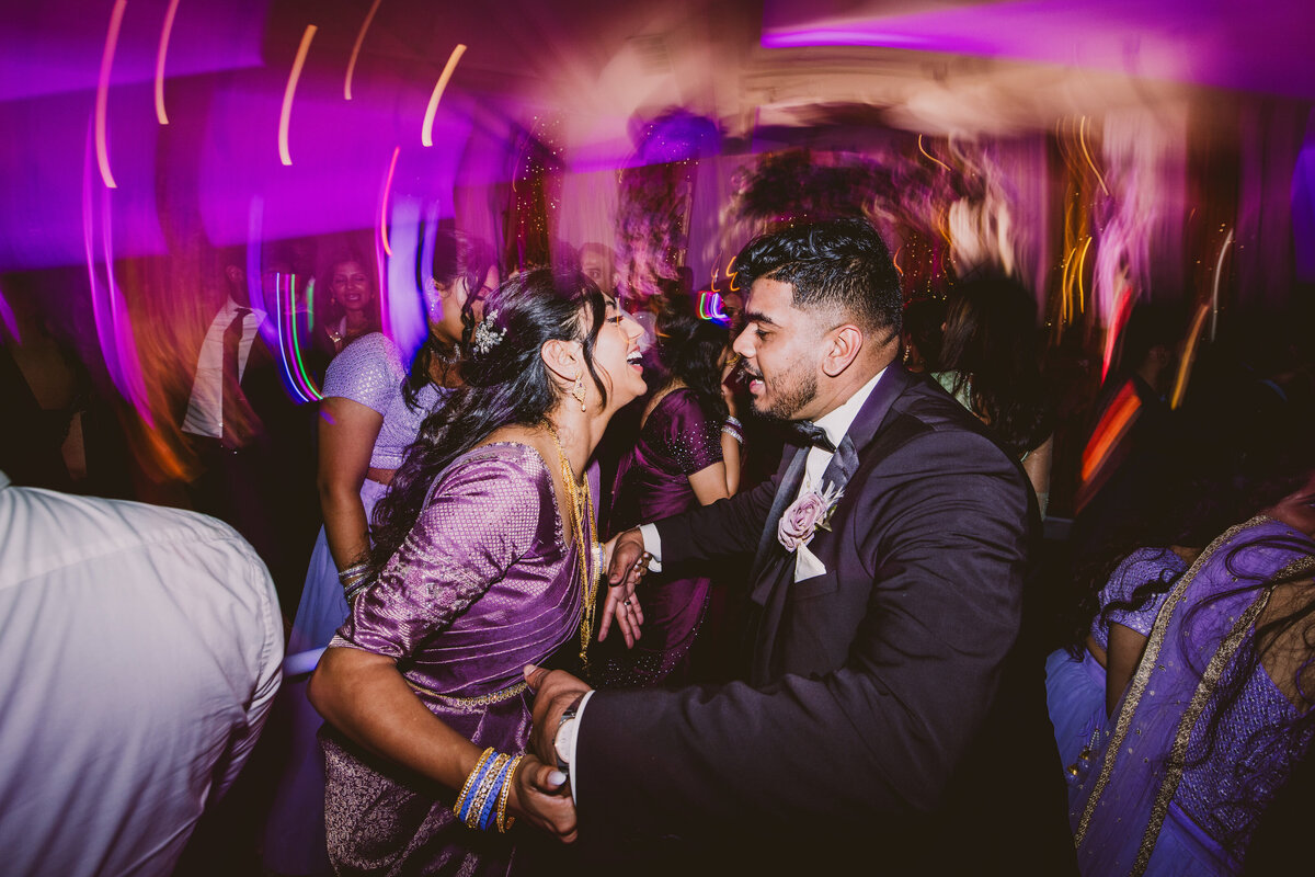 Indian christian malayali bride and groom dancing together on the dance floor during their wedding reception with the shutter dragging light across the frame