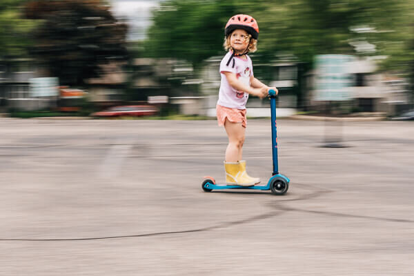 A creative panning photography technique shot of a young girl riding her scooter by Kate Simpson, Minneapolis lifestyle photographer.