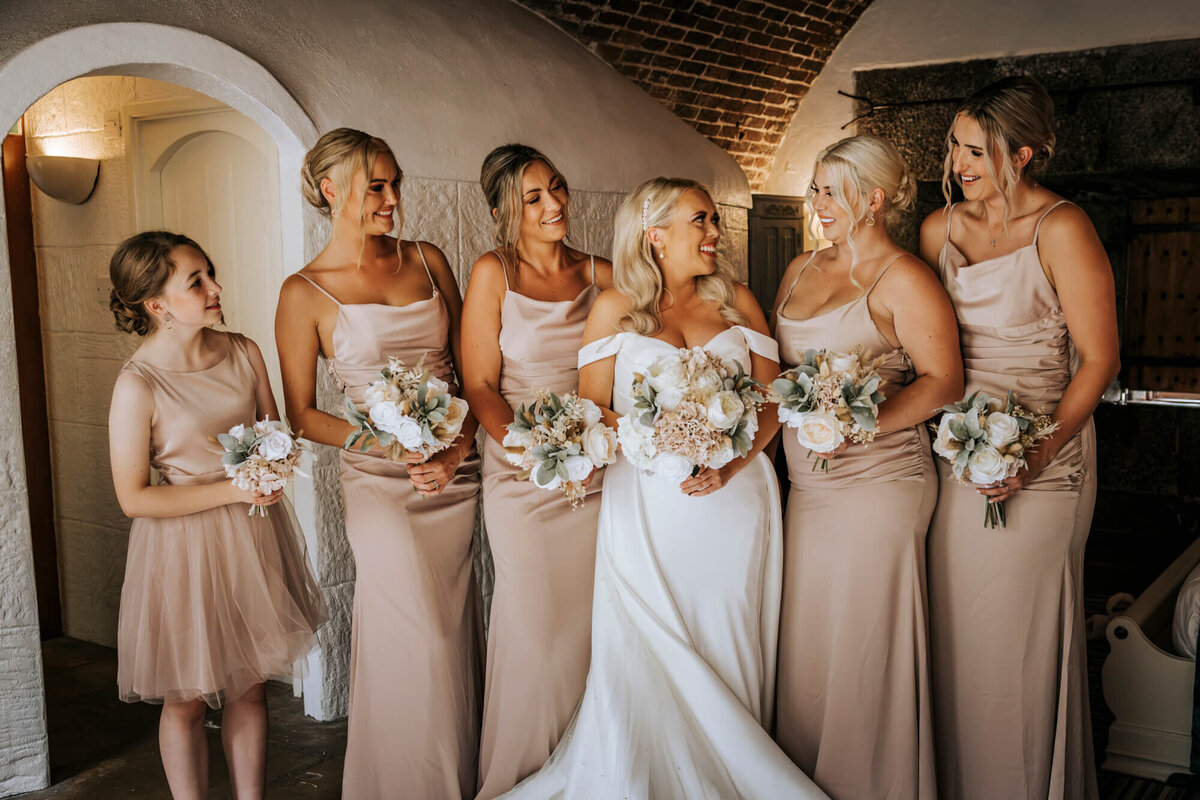 Bridesmaids and the bride standing in a line looking at each other