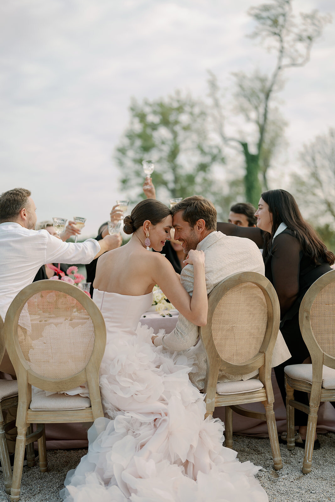 Bride, groom, and guests raising glasses during joyful outdoor wedding celebration at Château de Tourreau.