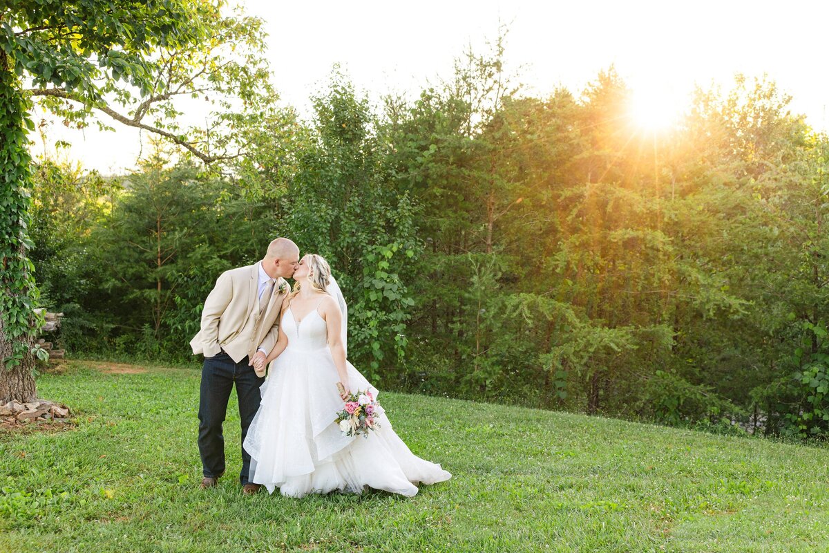 bride and groom kissing with sunset behind them