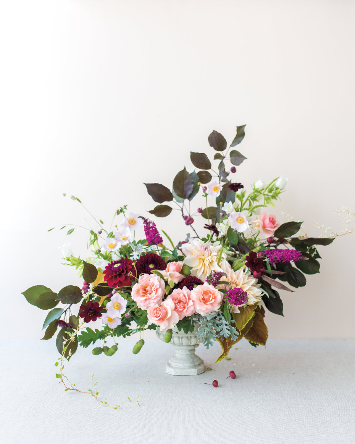 A beautiful, asymmetrical arrangement of colourful flowers and textured greenery.