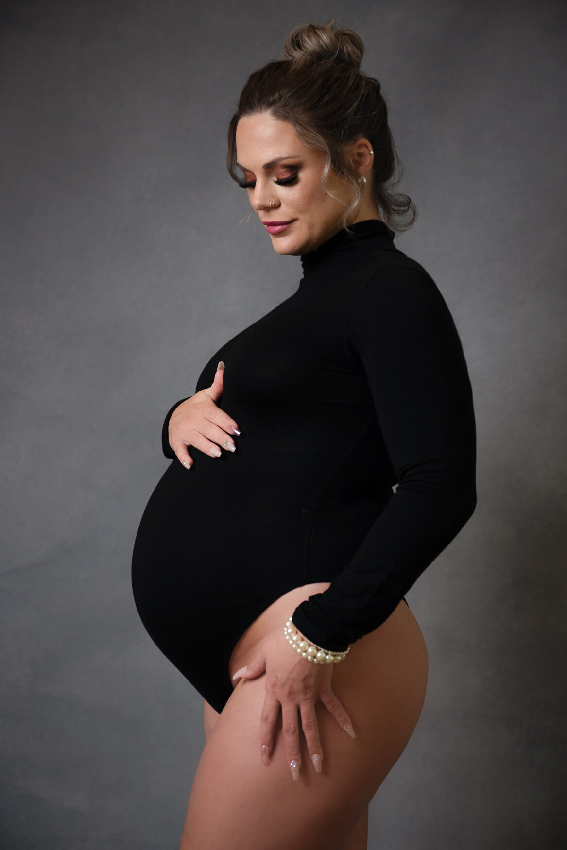 A maternity image of a woman touching her belly and smiling to it
