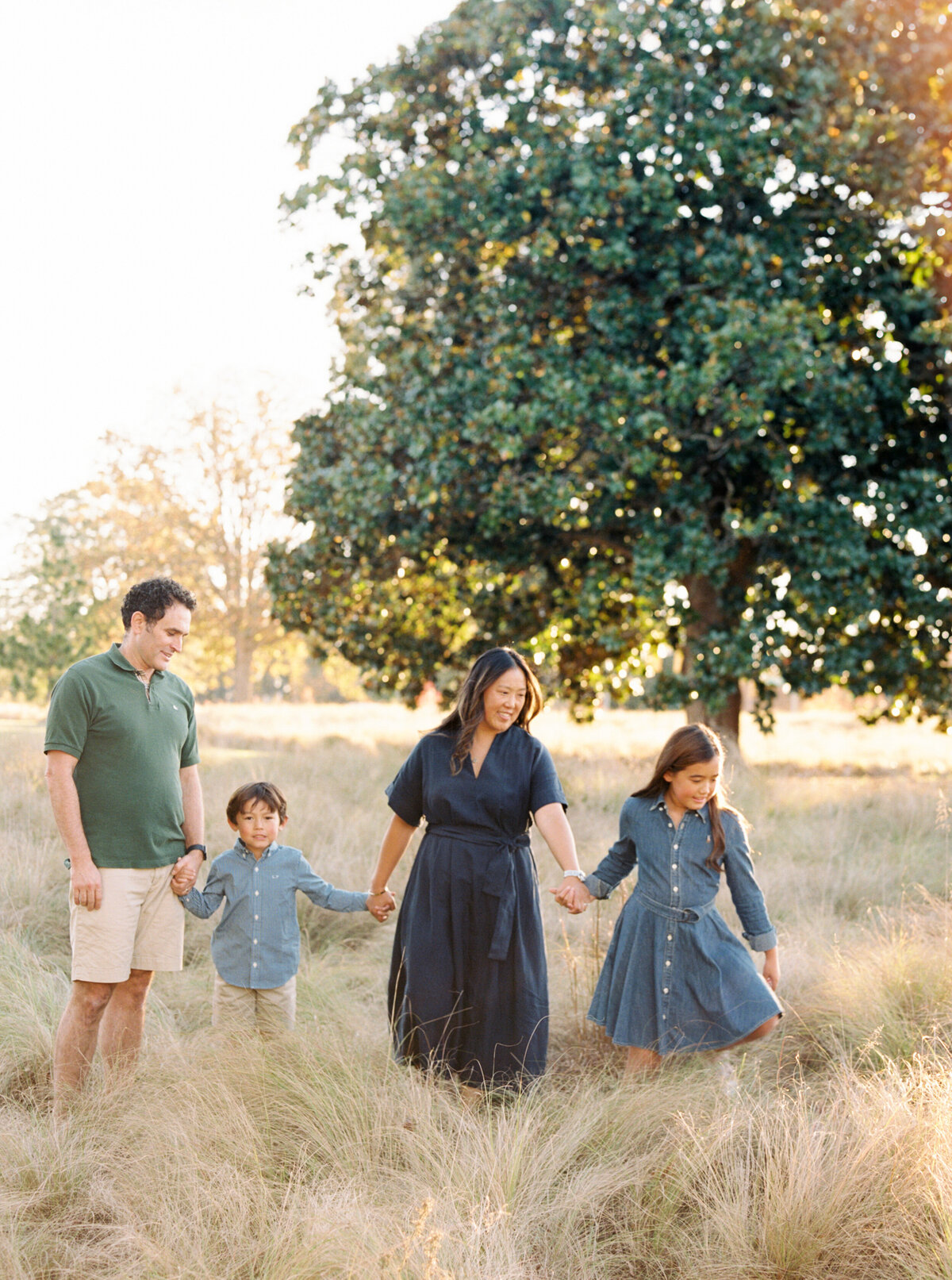 Family walks through a tall grass field. Image by Raleigh maternity photographer A.J. Dunlap Photography.