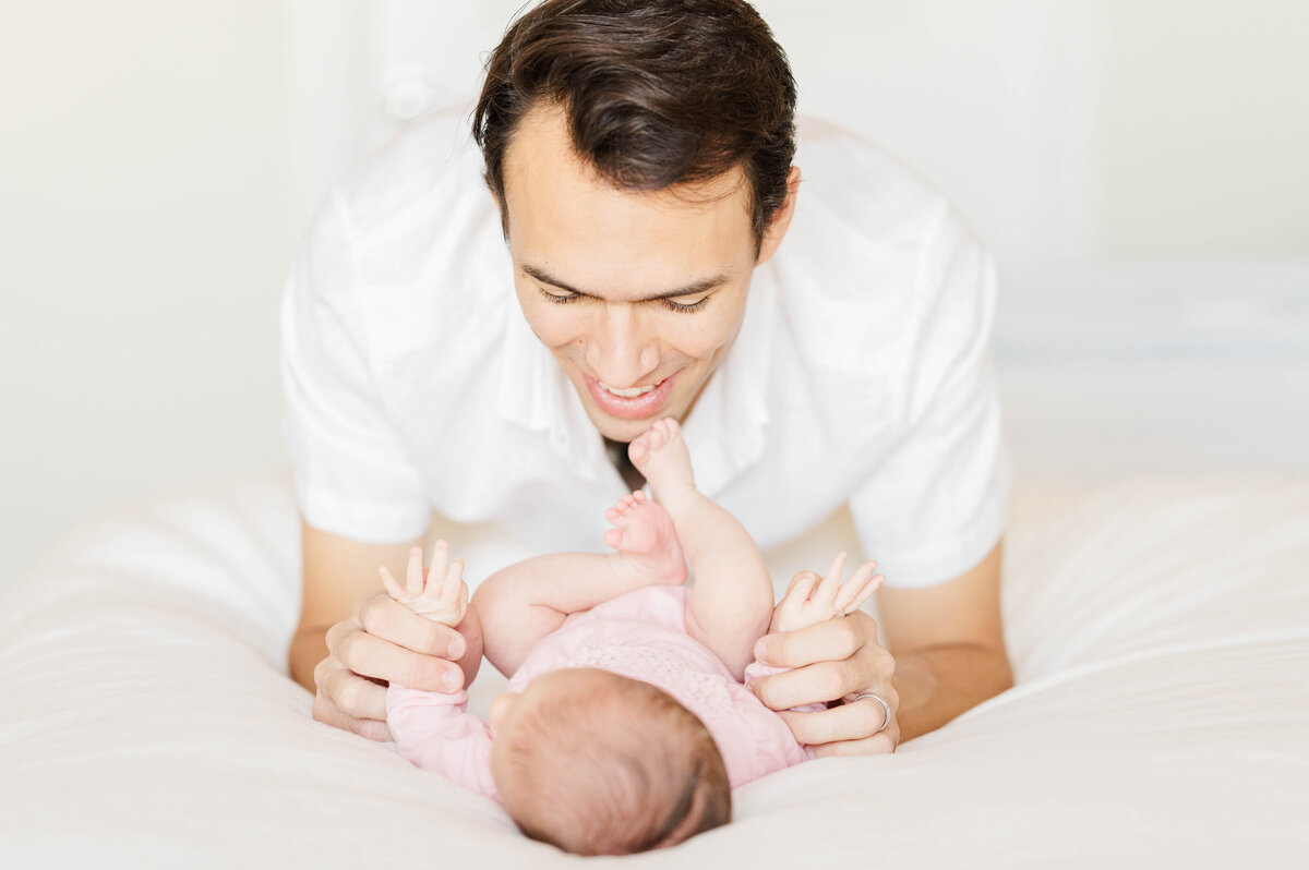 Newborn girl with dad looking at her taken in Westwood, MA by best Westwood newborn photographer
