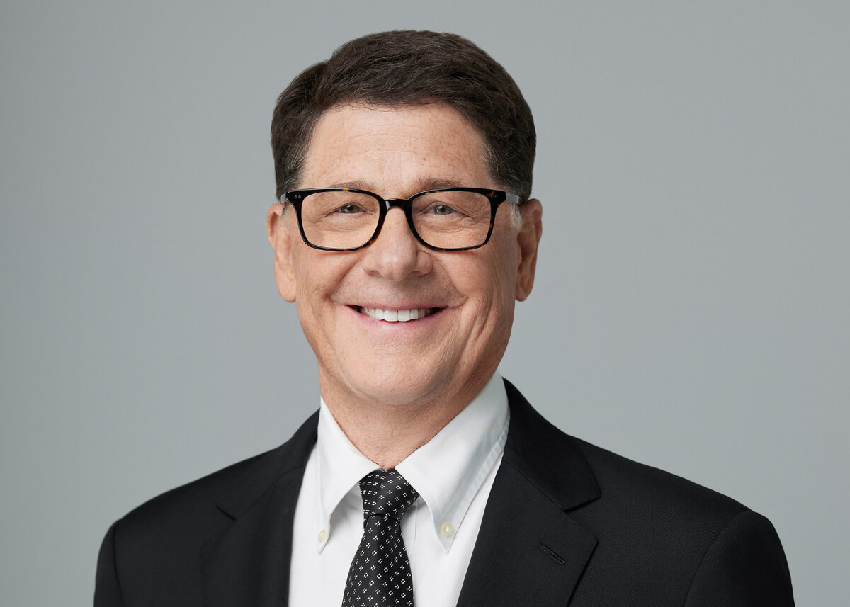 A man in a suit and glasses smiling