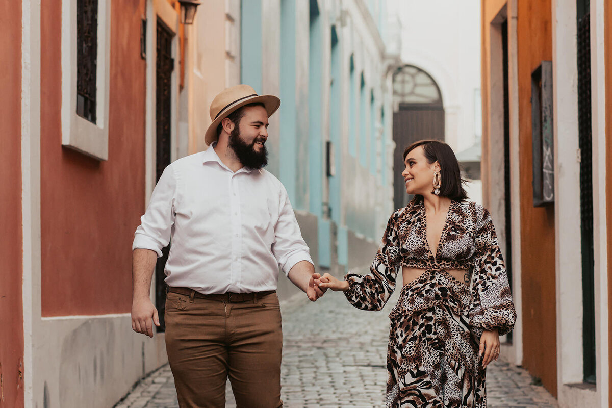 A couple holding hands while walking down a small alley 