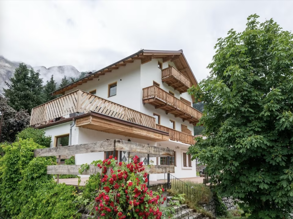 Traditioneel Oostenrijks chalet Haus Arlberg met besneeuwde bergtoppen in Sankt Anton am Arlberg.