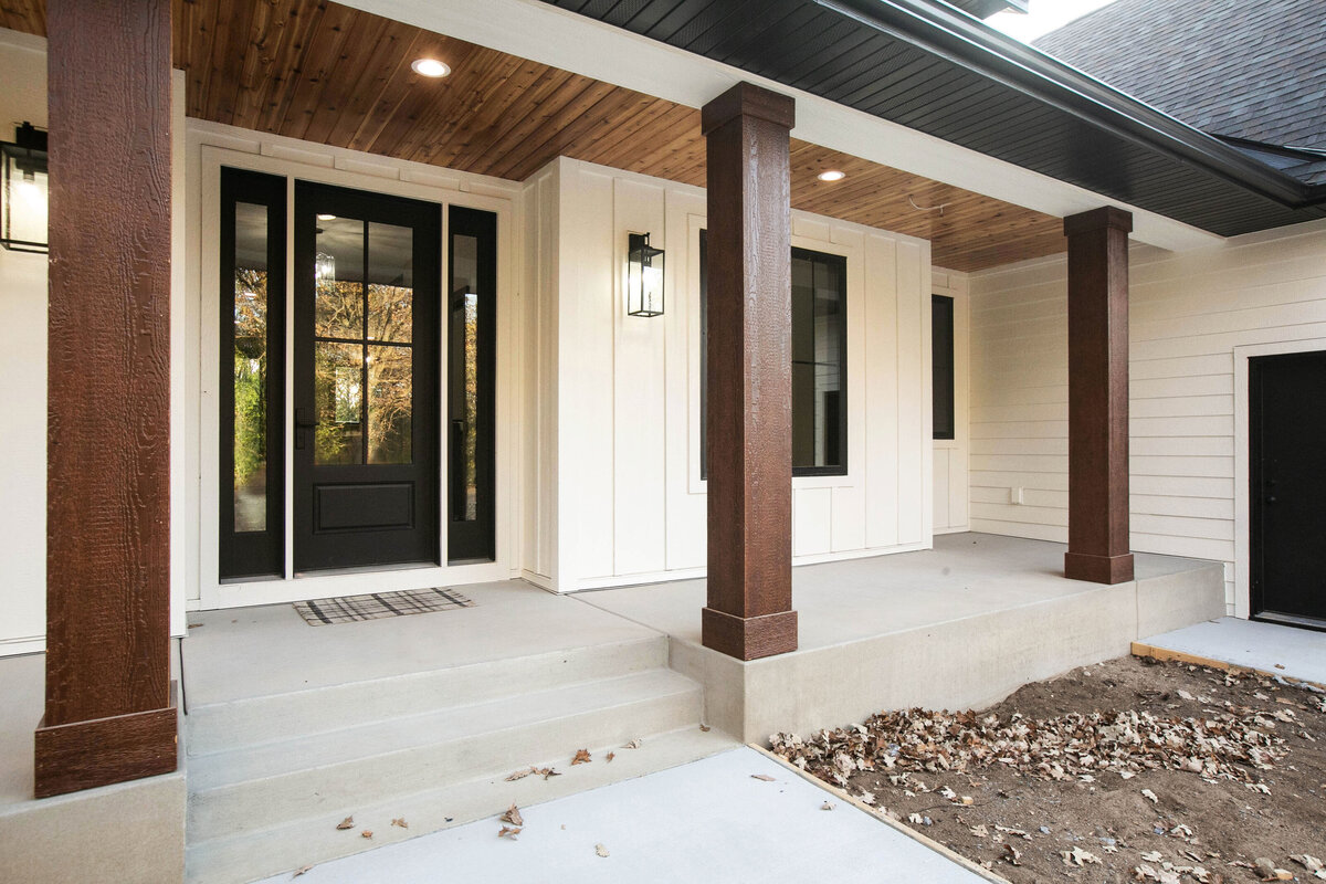 Exterior view of custom home in Big Lake Township, Minnesota with farmhouse details, cream siding, wood pillars and front porch built by Cornerstone Custom Builds