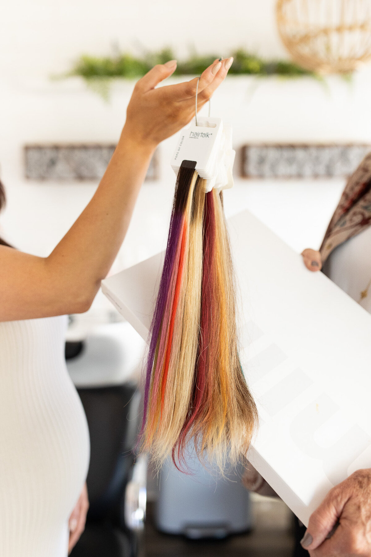 Hair stylist holds color palette samples of hair at her salon.