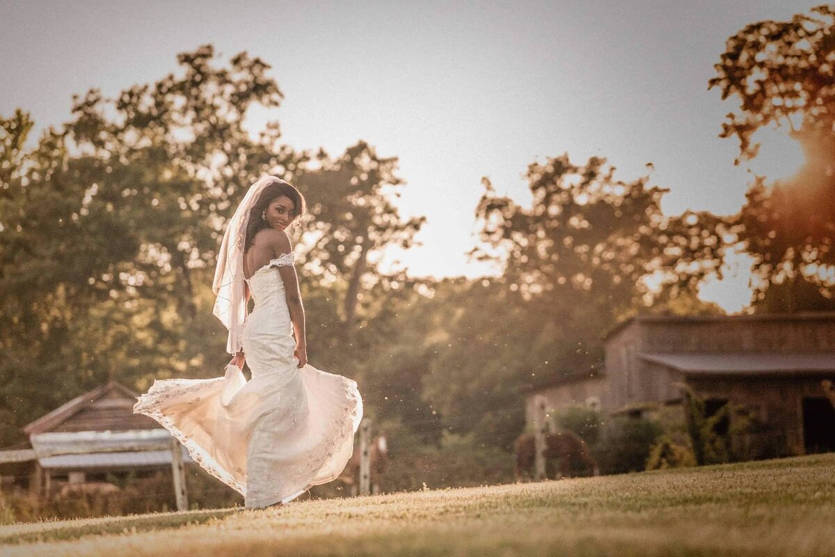 A bride looking back as she walks across a field