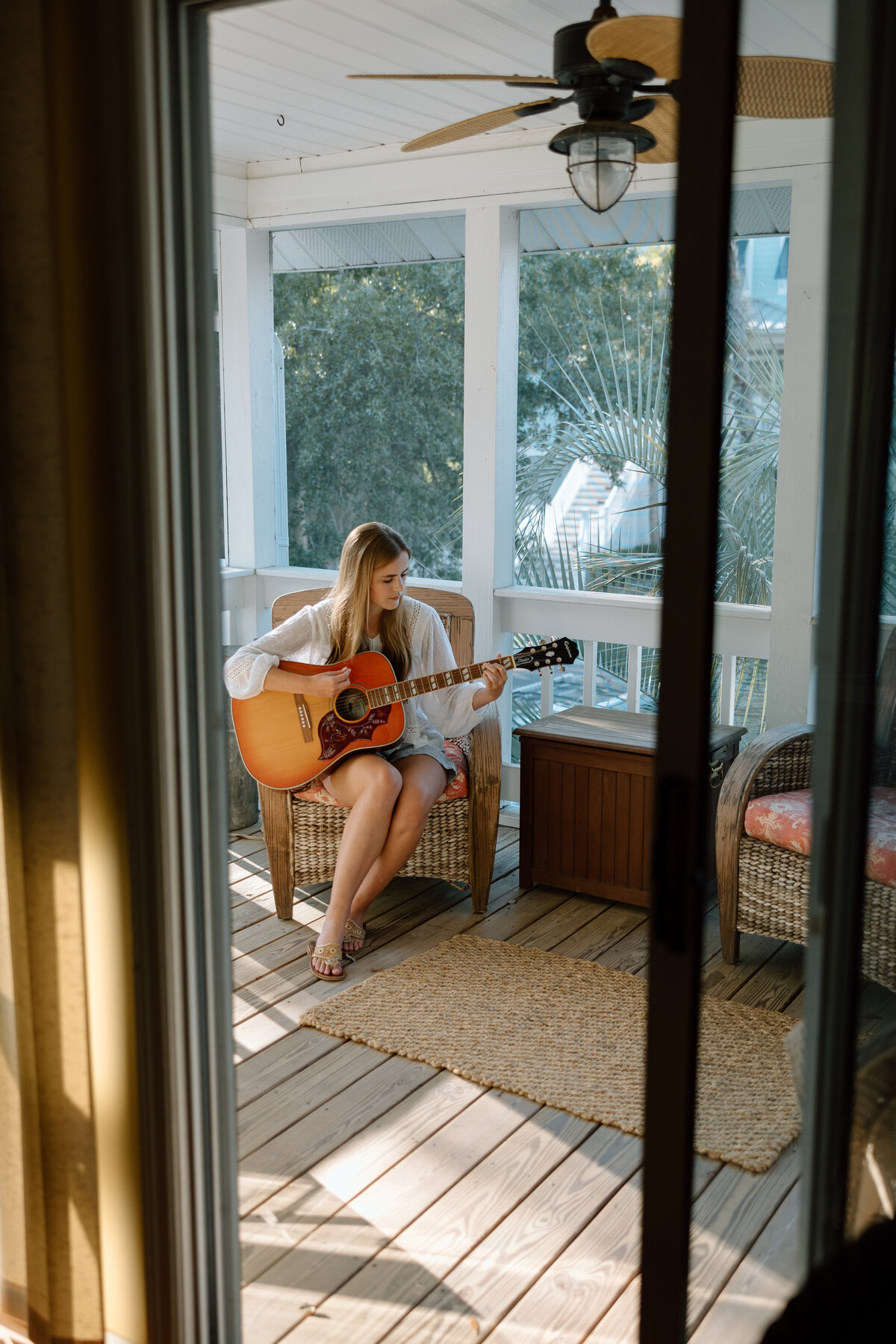 Senior photos at Edisto beach, senior sits on porch with a guitar