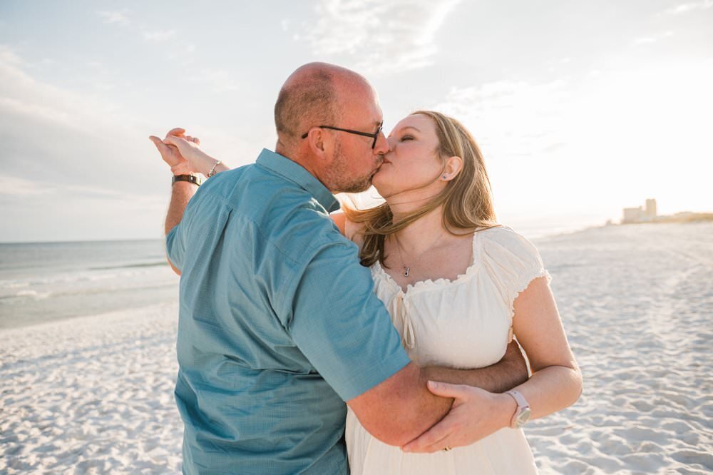 husband kissing wife on beach