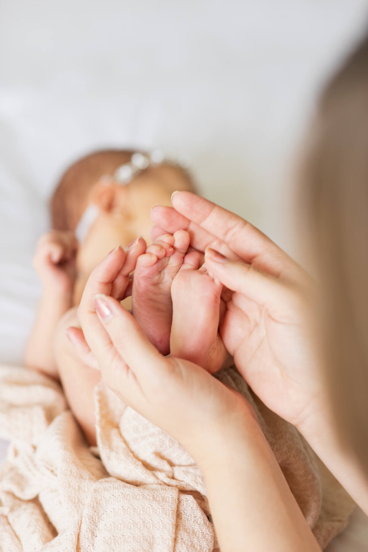 New mom holds the feet of her newborn baby