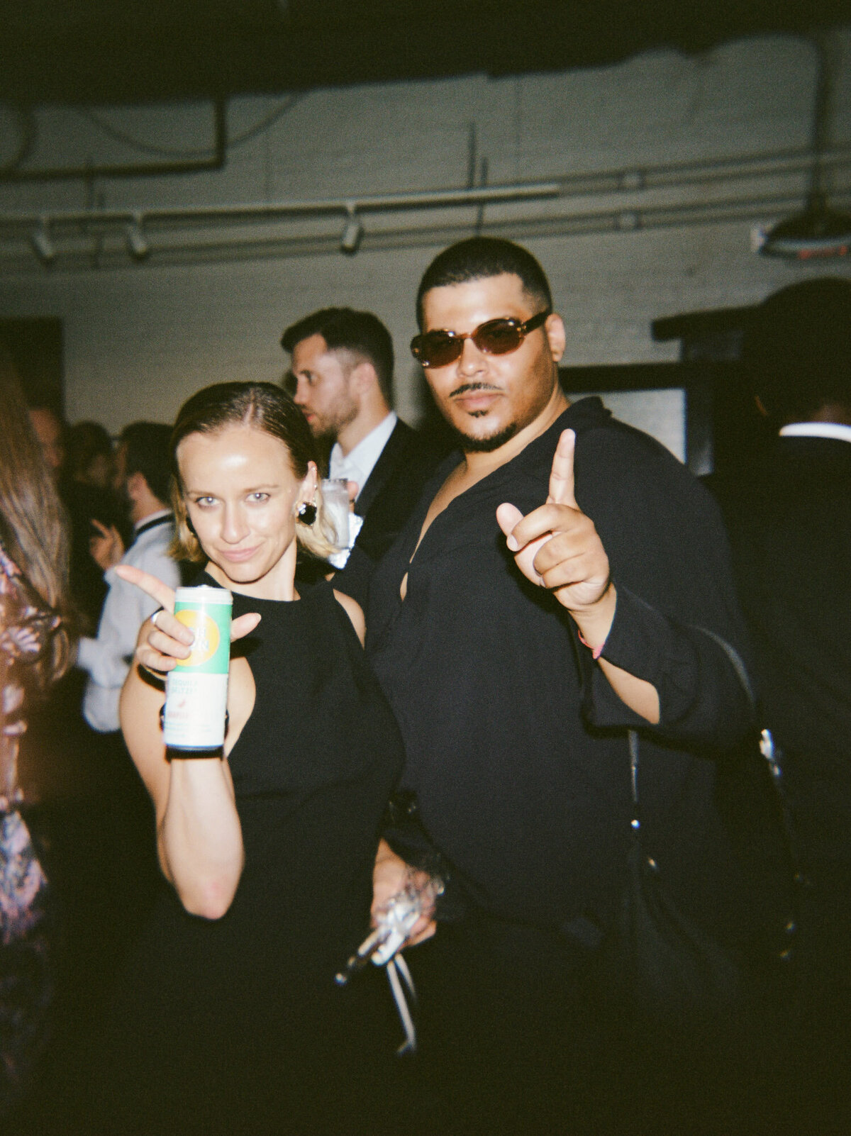 guests pose for a photo with drinks at a Detroit wedding afterparty in a warehouse
