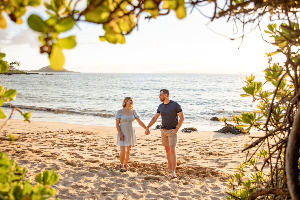 Maui Family Photographers capture man and woman holding hands on beach looking at one another