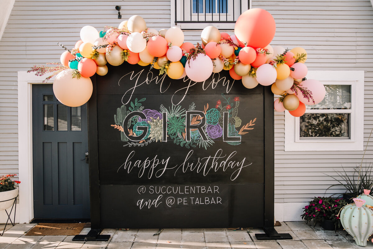 Black birthday backdrop for a succulent bar with pink balloon arch