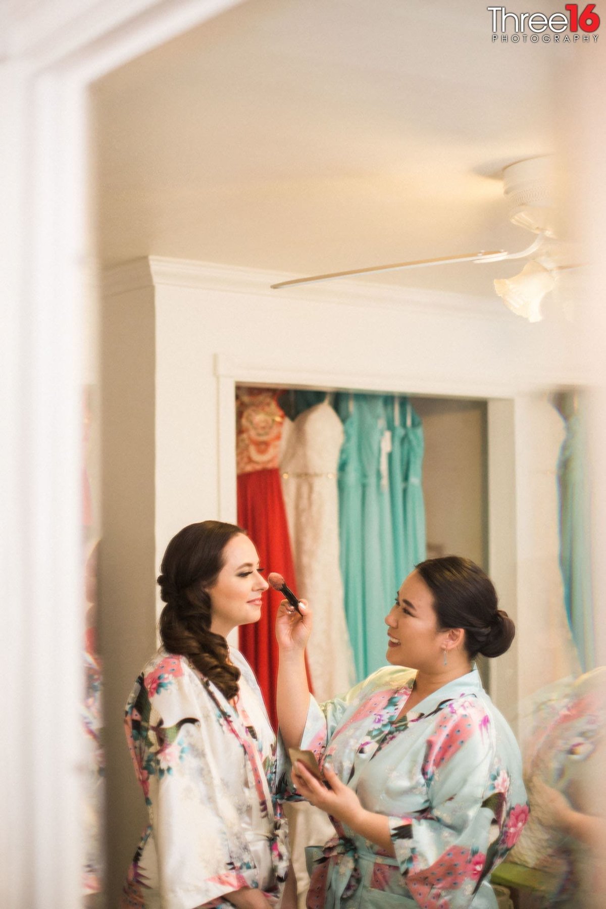Bridesmaid applies makeup to the Bride before getting dressed