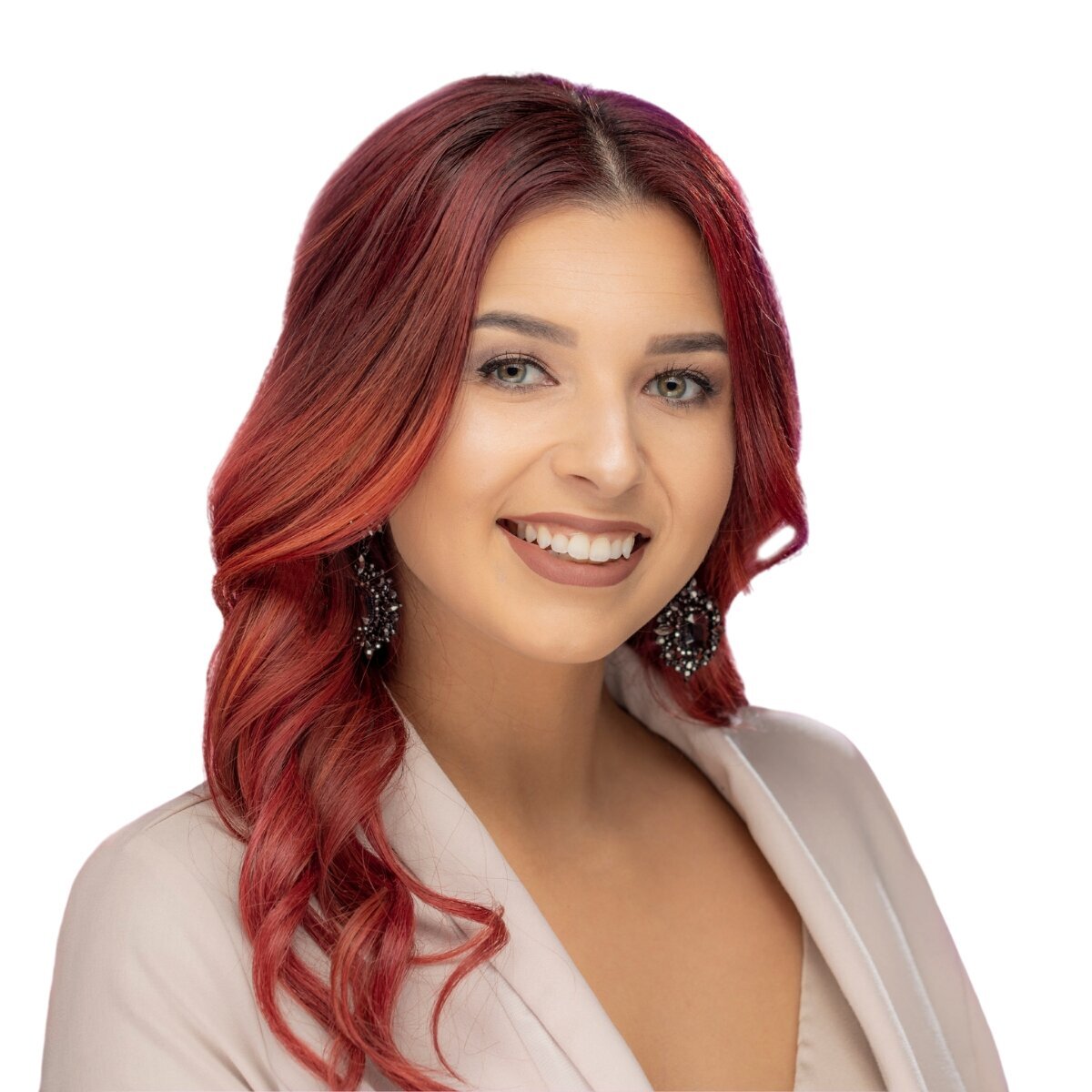 Stylish woman with bright died red wavy hair smiles at camera in business attire for a professional sacramento headshot.