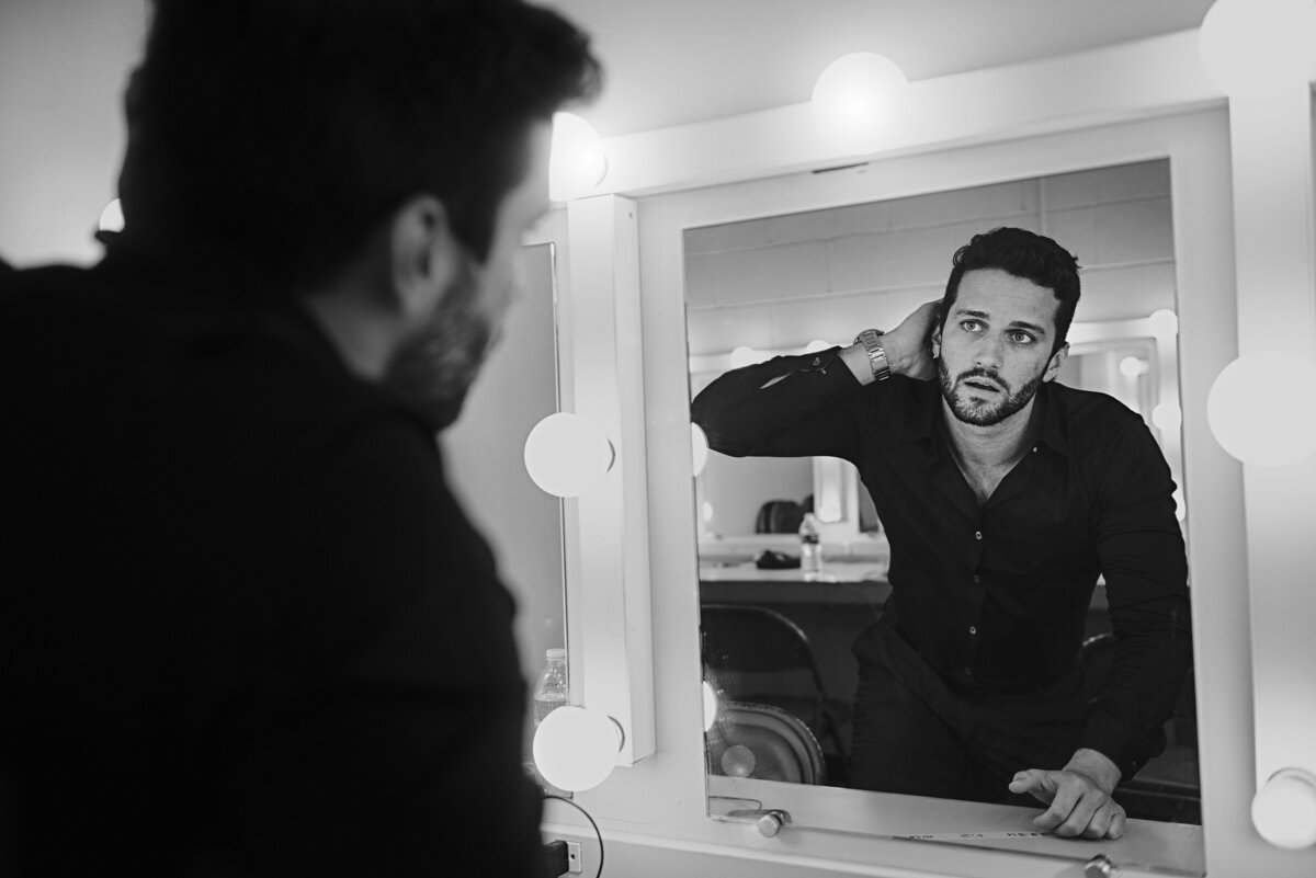 The reflection of a person in a mirror fixing their hair