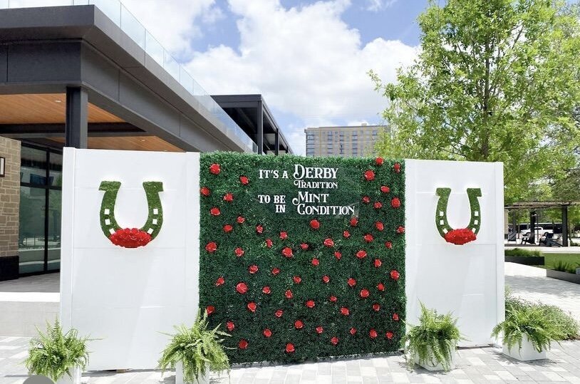 Derby themed backdrop design with greenery, red flowers and horseshoes