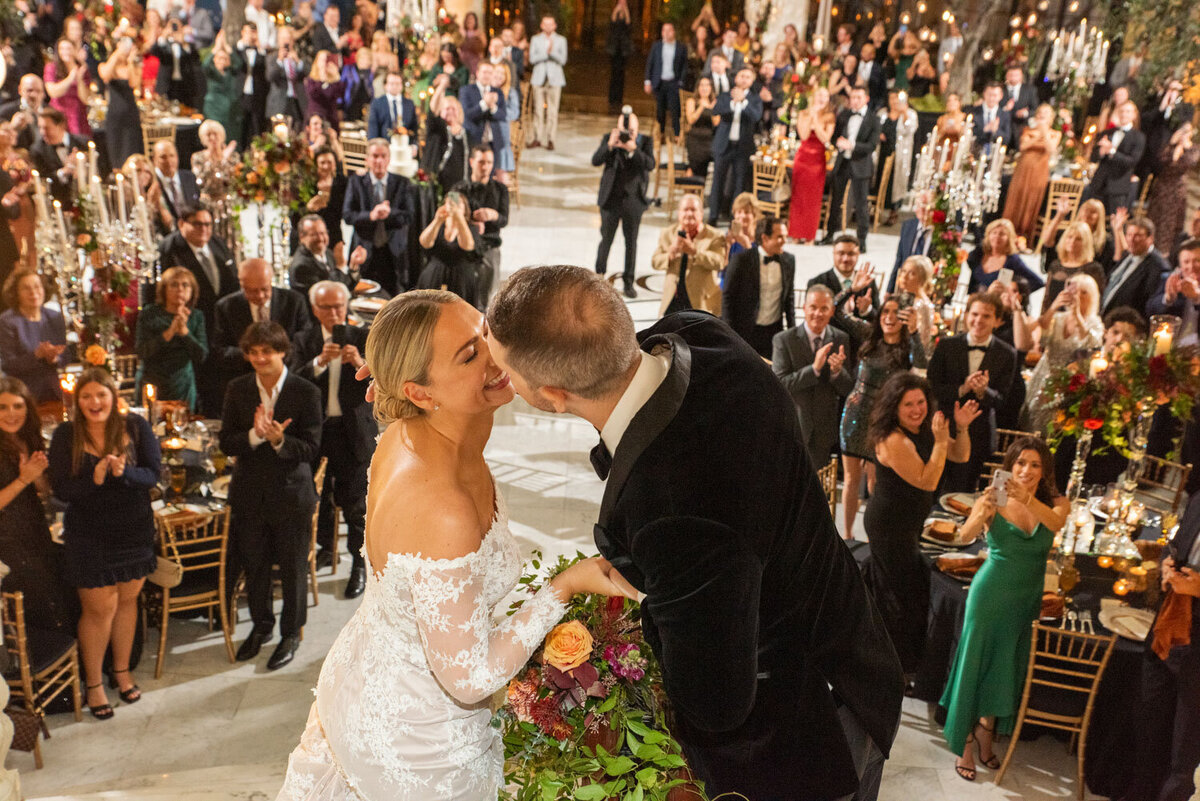 A bride and groom kissing in front of a crowd of people