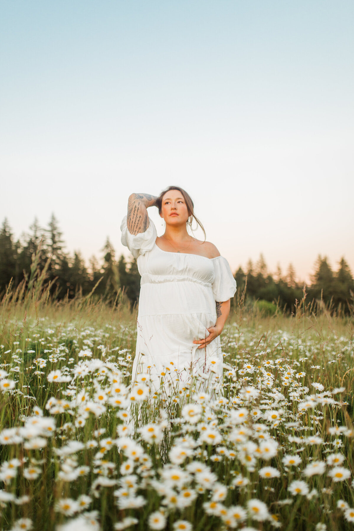 Pregnant woman standing in a field of white flowers