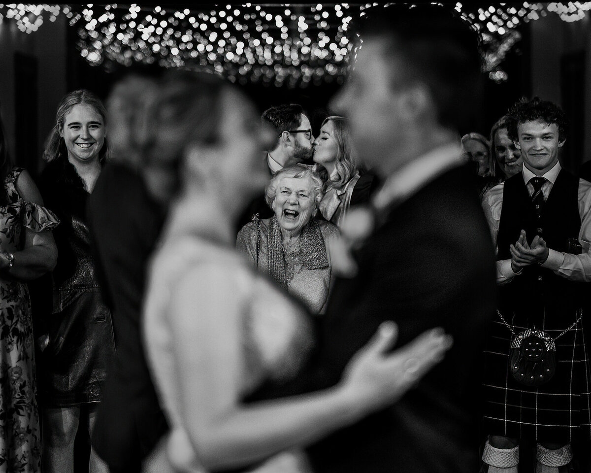 Bride and groom with guests smiling in background