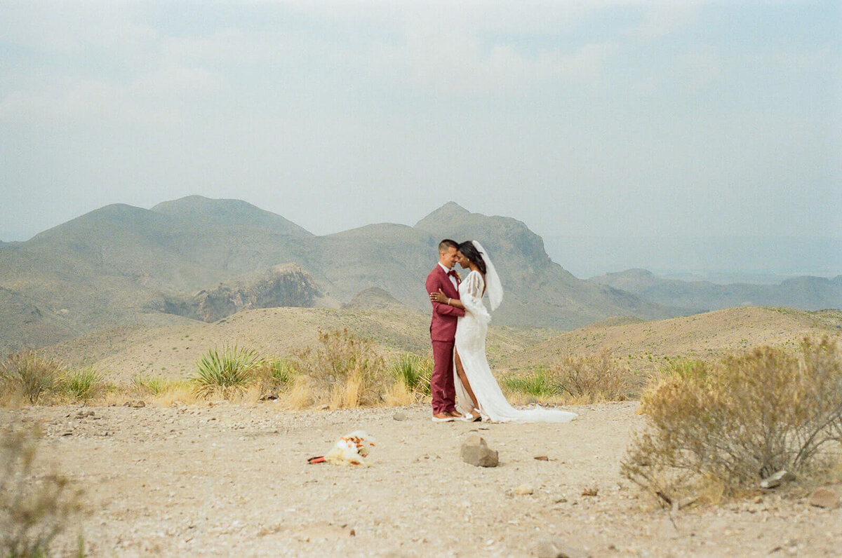 couple kissing with desert and mountains behind them