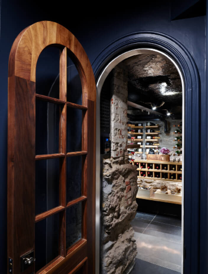 Boston Interior Designer designed a wine cellar with a custom curved door and modern shelving in a brownstone renovation design project in the South End.