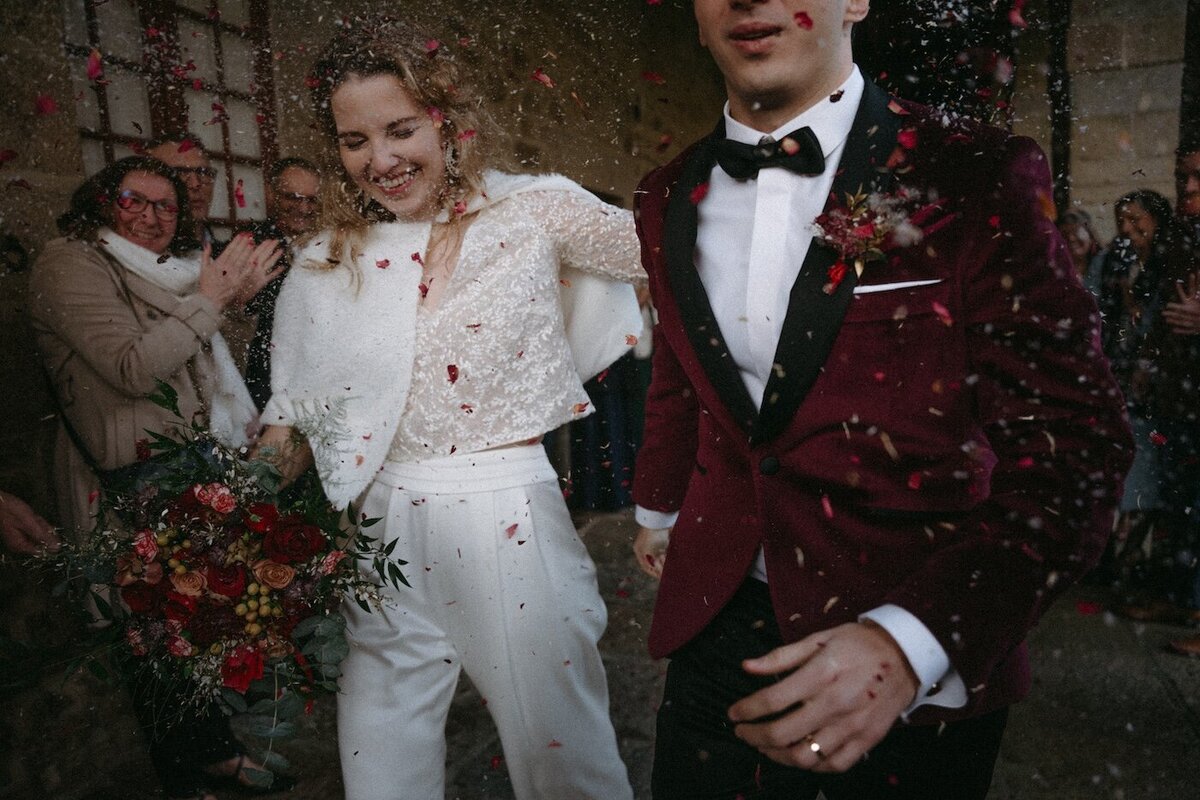 Mariés sous une pluie de pétales, sourires éclatants après la cérémonie religieuse. Photo Kamescop, spécialiste du reportage mariage en Bretagne.