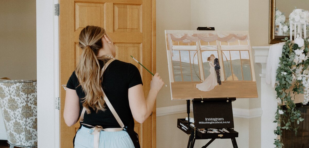 Live Wedding Painter, Olivia Andruss, takes a step back to ponder the progress of her current painting at Flying Horse Ranch