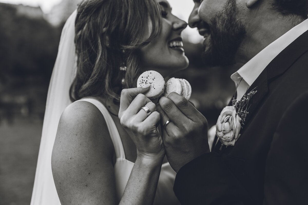 Bride laughing and feeding groom a macaron during picnic